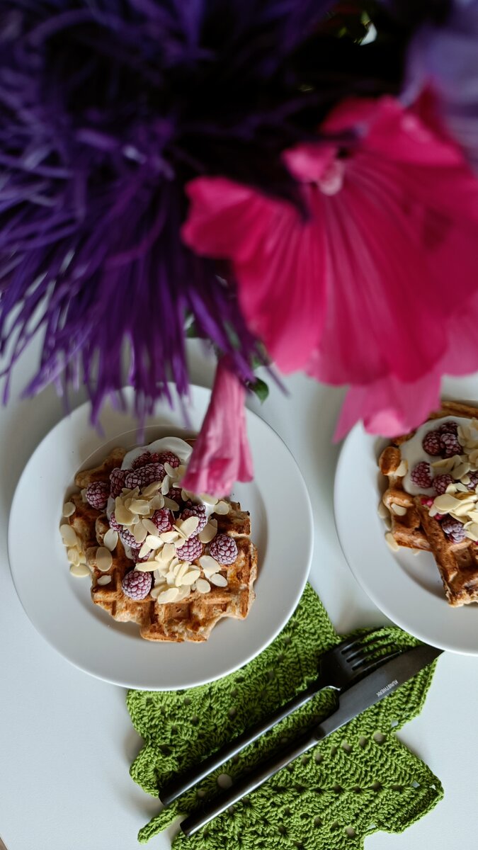 Хрустящие вафли, украшенные сметаной, замороженной малиной и миндальными лепестками