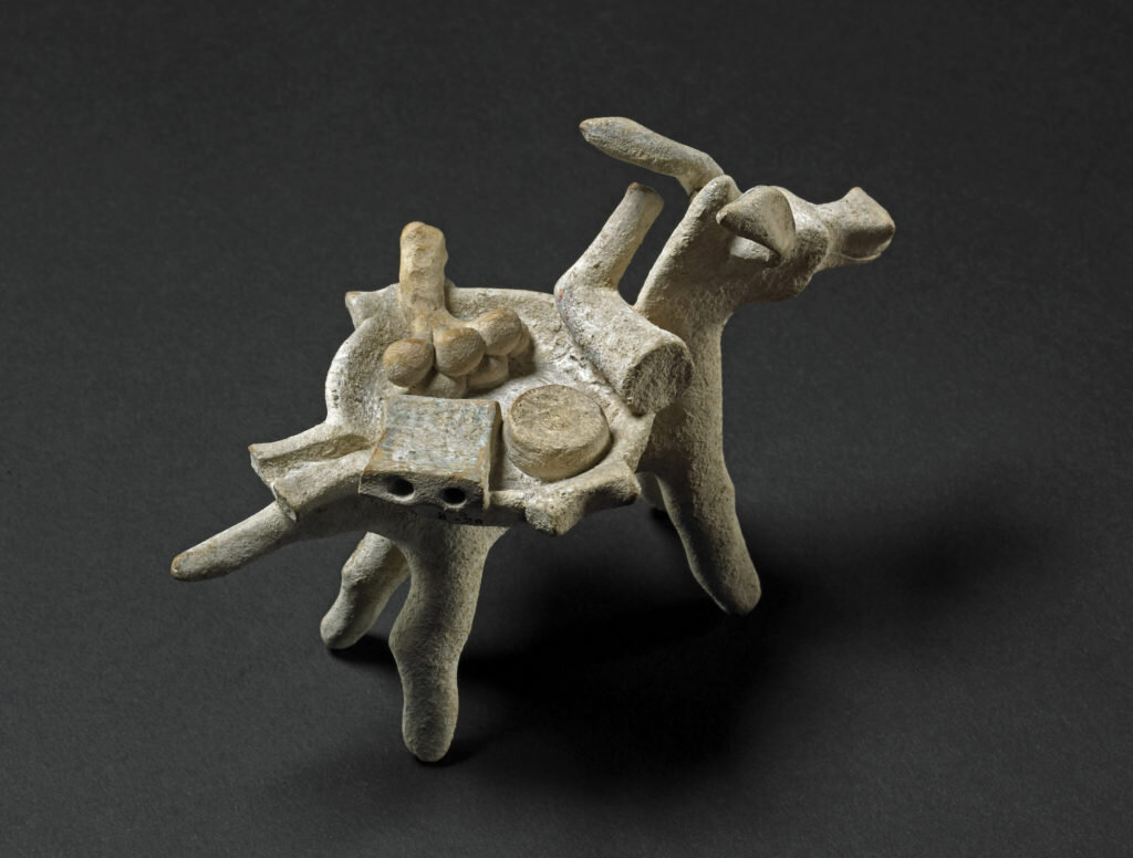 
Терракотовая фигура мула, несущего мортирию (миску для измельчения). Внутри пестик, терка для сыра, круглый сыр и пучок чеснока. Греция, около 350 г. до н.э.
