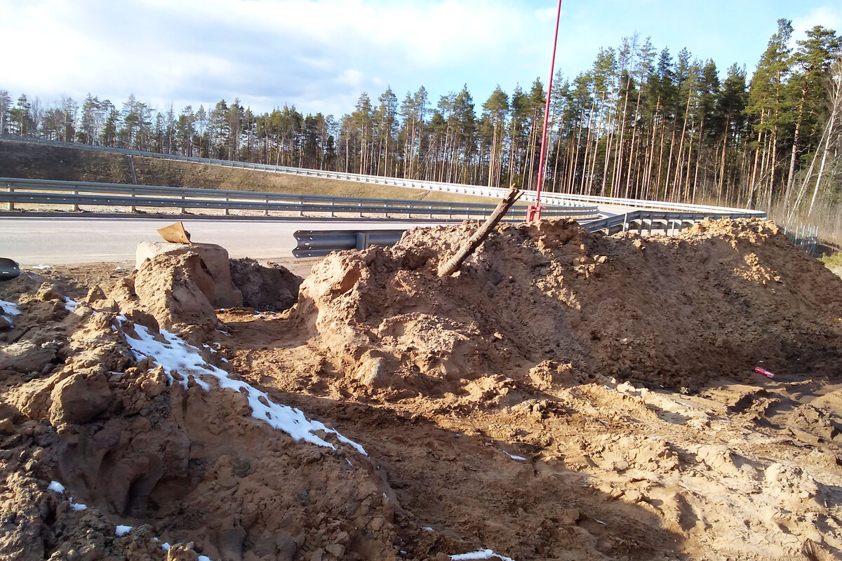 Куча песка, бетонный блок, металлическое ограждение и шлагбаум