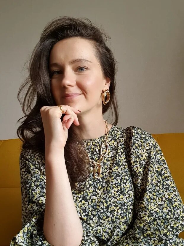 На фото перегруженный образ с крупной цепью и ярким платьем