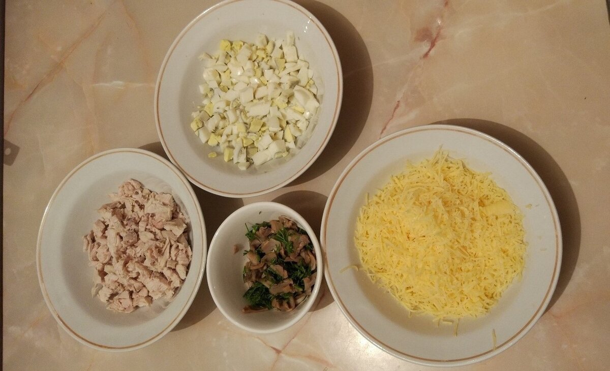 Отвариваем яйца и куриное мясо. Вымыть зелень, мелко порезать. Сыр натереть на мелкой тёрке. Яйца куриную грудку мелко порезать.
