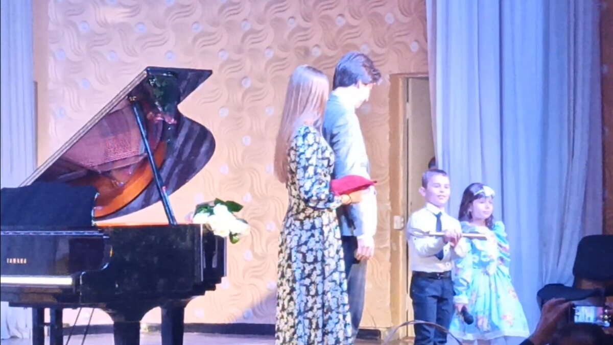 Выпускники театрального отделения Каспаров Армен и Бровцева Дарья передают малышам символический ключ от школы.