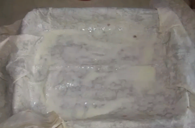 Кладу в форму первый лист лаваша и смазываю его смесью из ряженки с яйцом