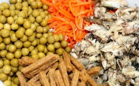 Шаг 1 Убираем шпрот хвостики, а с горошка слить жидкость. Выкладываем в глубокую тарелку рыбу, разминаем вилкой. Добавляем морковь, зеленый горошек, сухарики.