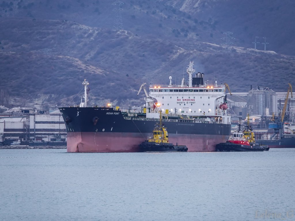 Упрямые буксиры заводят в порт судно.