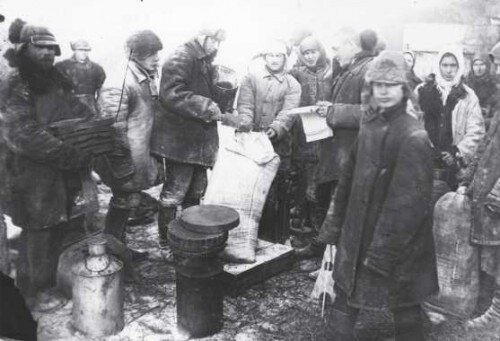 Выдача колхозникам продуктов за "трудодни" (Украинская ССР, 1933г.). Советское государство не платило колхозникам денег. Они получали "трудодни" (запись в учетной книге колхоза), по которым им впоследствии выдавалась еда, и иногда какие-то дополнительные предметы типа одежды. Что им выдавать - решало государство. То есть колхозник, в отличие от городского работника, вообще ничего не мог купить: не то чтобы из-за дефицита товаров в магазине, а из-за отсутствия денег на руках. Бегство из колхоза означало в отсутствие денег голодную смерть. (Im.source: Wiki)
