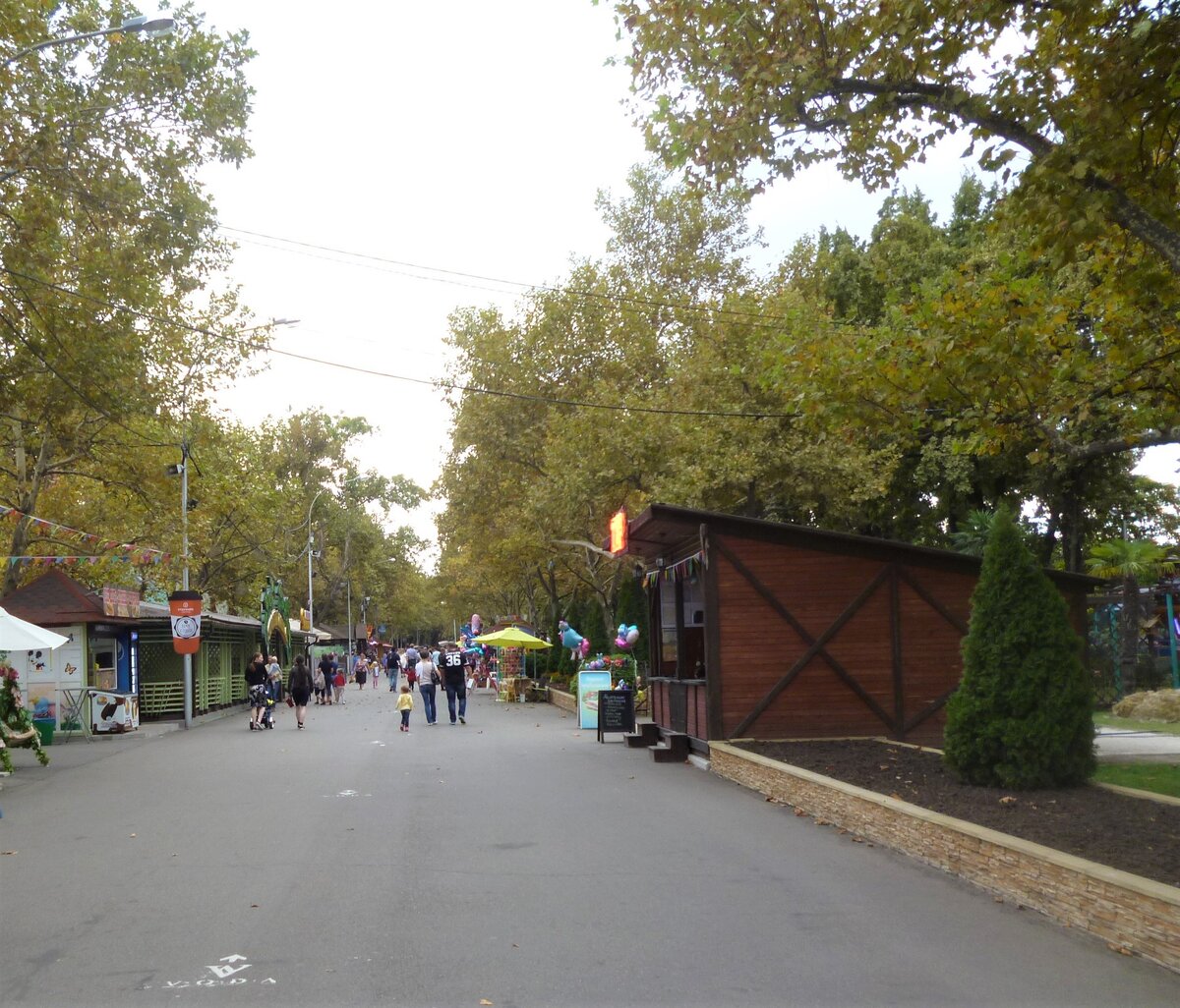 А это центральная аллея: здесь находятся  летние кафе,
В конце этой аллеи есть спортплощадки, где можно поиграть в бадминтон, теннис, волейбол, или заняться гимнастикой.
А на параллельной аллее слева есть пляж у реки Кубань, недалеко от которого летняя волейбольная площадка с песком.