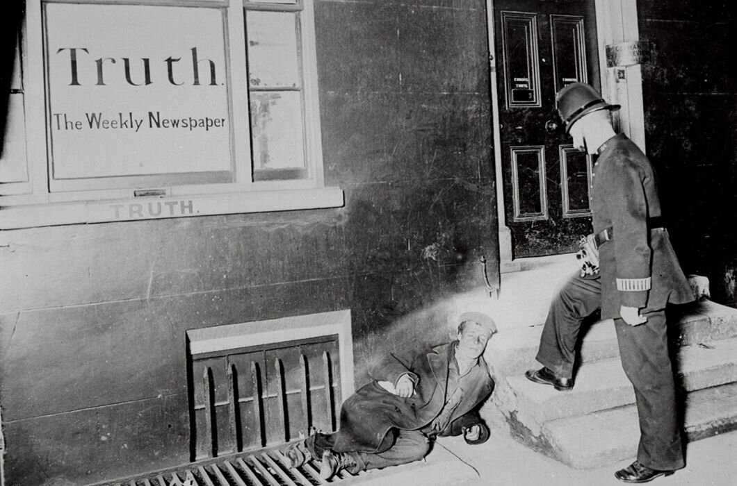 Полицейский осматривает уснувшего человека у редакции газеты “Truth” («Правда»)

