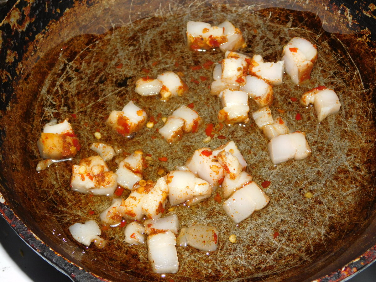Дно сковородки испачкано маслом и сало с перцем Чили.