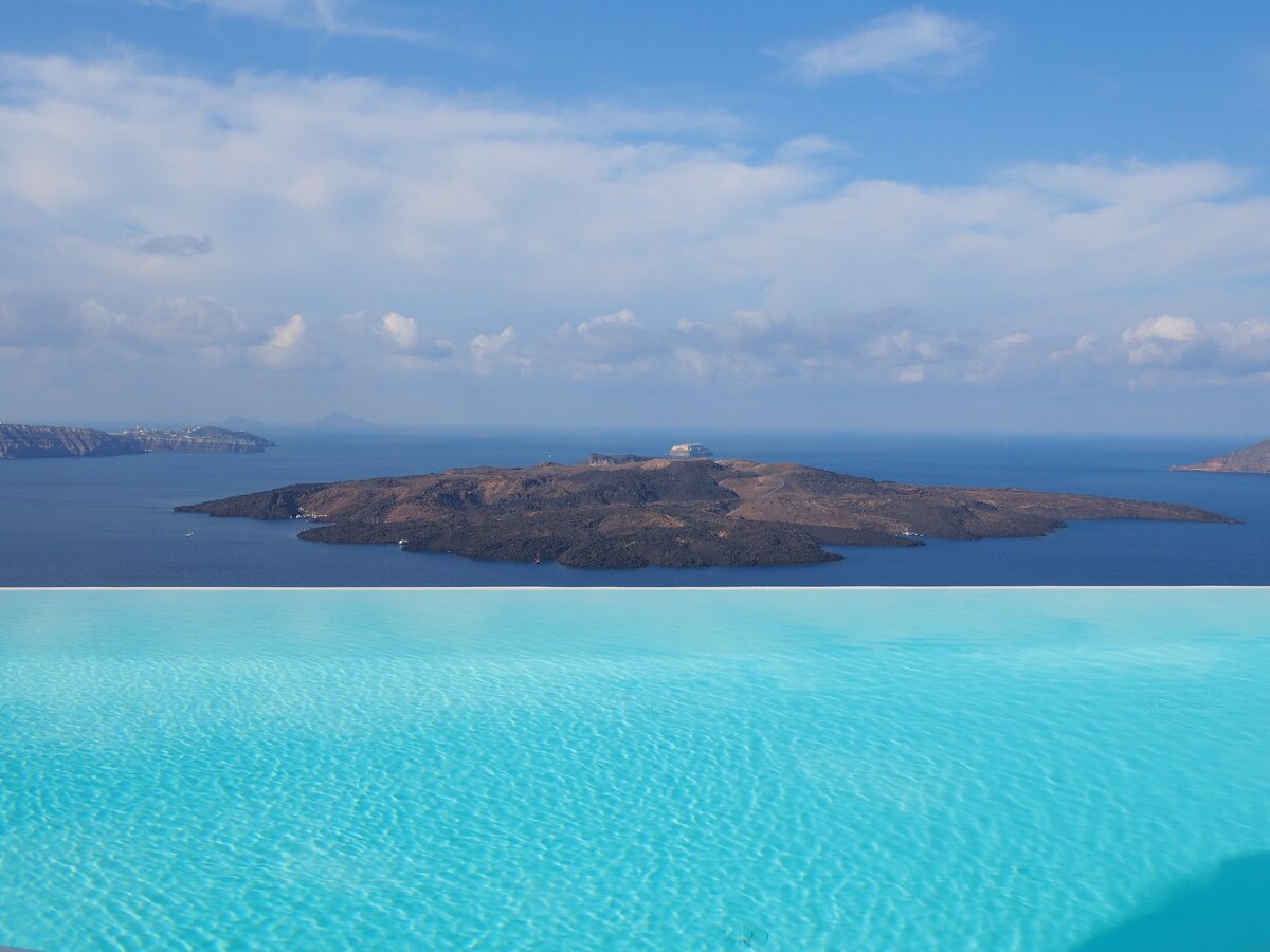 Вид на вулкан острова Неа Камени из инфинити бассейна в одном из отелей Фиры