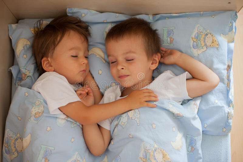 два младенца спят вместе в кроватке