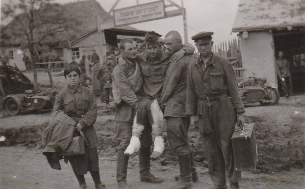 Явно постановочная фотография сделанная предположительно где-то на Украине. С трудом можно разобрать надпись на сборном пункте военнопленных: "Главюгзаготскот" ... райконтора. Один из военнопленных в комбинезон техника, один со скаткой через плечо.