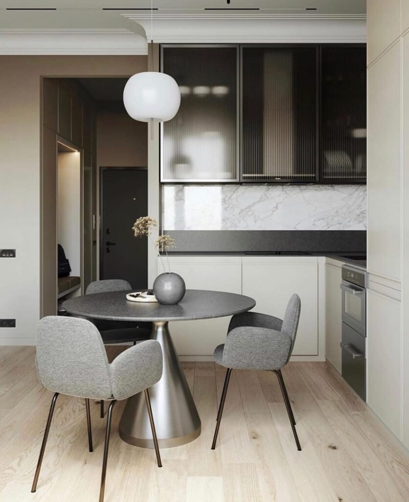 В основе интерьера — песочный оттенок стен, дополненный светлым паркетом теплого оттенка и контрастные серые и черные акценты, представленные предметами мебели и декора. Дизайн достаточно простой, но смотрится нарядно благодаря контрастам и красивым богатым фактурам — мрамору, камню, стеклу, древесине.