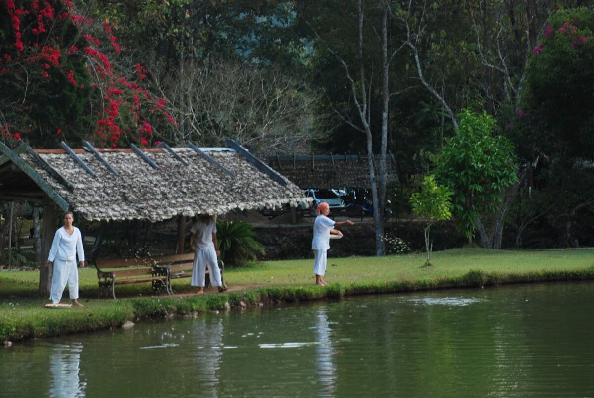 Послушники в белых одеждах кормят рыб. Вода в пруду просто бурлит в этот момент
