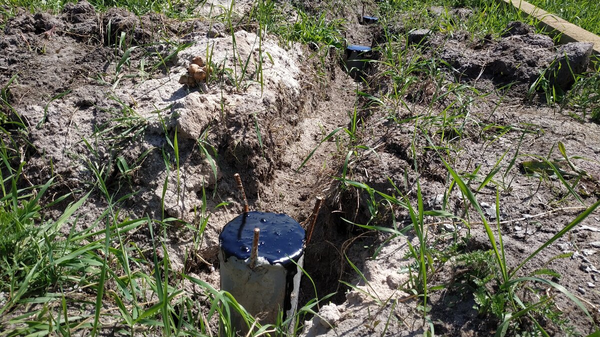 Покрытие столбов фундамента битумной мастикой.