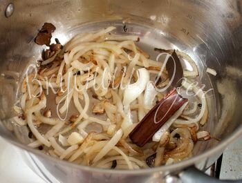 Лук нарезаем тонкими кольцами. Картошку режем кубиками. В кастрюле с толстым дном на среднем огне разогреваем 2 ст.л. растительного масла. Кладем лук и жарим, помешивая, 5 минут. Добавляем кардамон, гвоздику, перец горошек, корицу и лавровый лист. Жарим, помешивая, еще 1 минуту. 