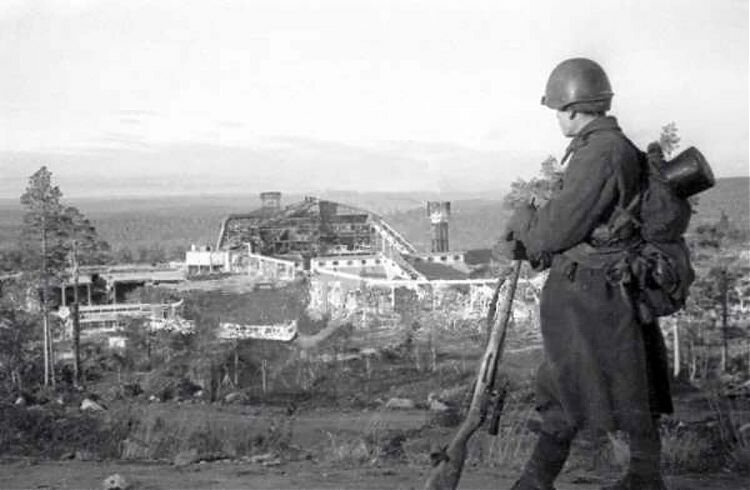 Советский солдат на фоне разрушенного немцами комбината в Колосйоки (ныне Никель). 