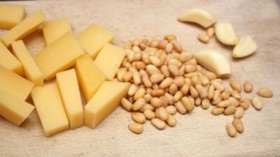     Грибы тщательно промываем, даем стечь воде и нарезаем тонкими ломтиками. Пармезан нарезаем мелкими кубиками примерно 0,5х0,5 см или тонкими пластинками, чем тоньше тем вкуснее. Чеснок, также максимально мелко режем ножом. Кедровые орешки обжариваем на сковороде с антипригарным покрытием до золотистого цвета, примерно 3-4 минуты.   