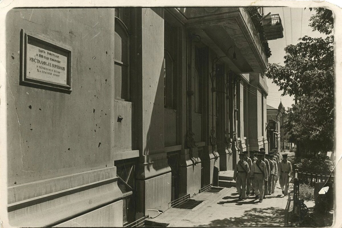 Советские моряки идут по Московской улице мимо дома, где в 1918 был штаб 10 КА, (хорошо видно памятную табличку) лето 1942 г. Снимок Георгия Зельмы. 