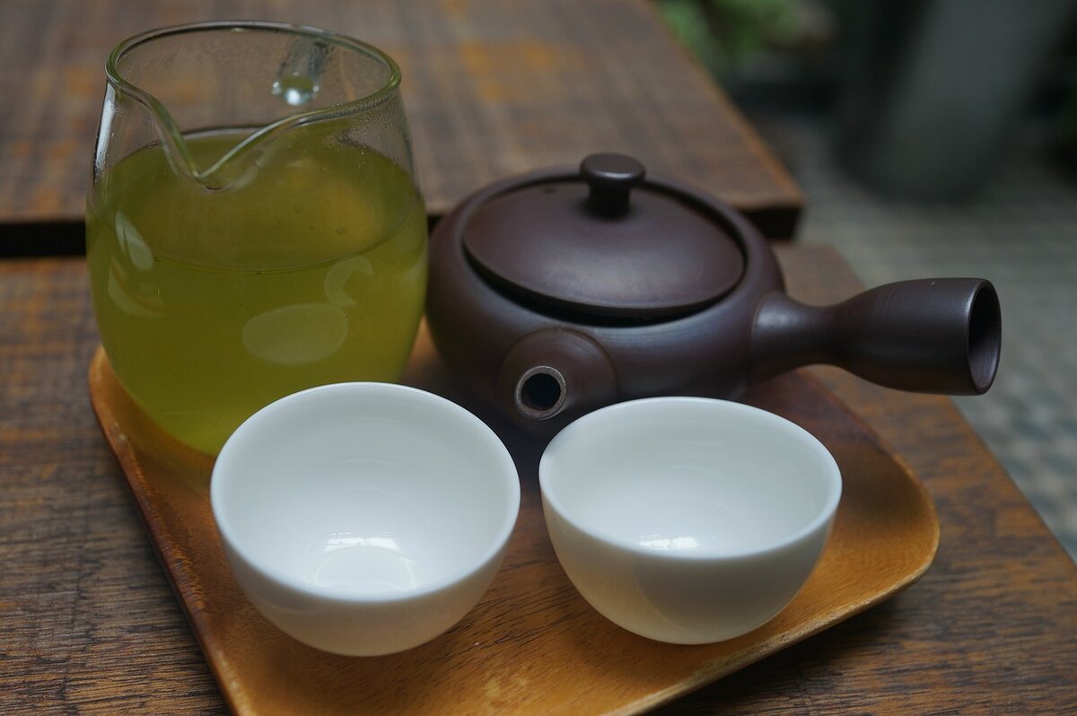 Двое пили зеленый. Кувшин с зеленым чаем. Напитки из глины. Девушка пьет зеленый чай.