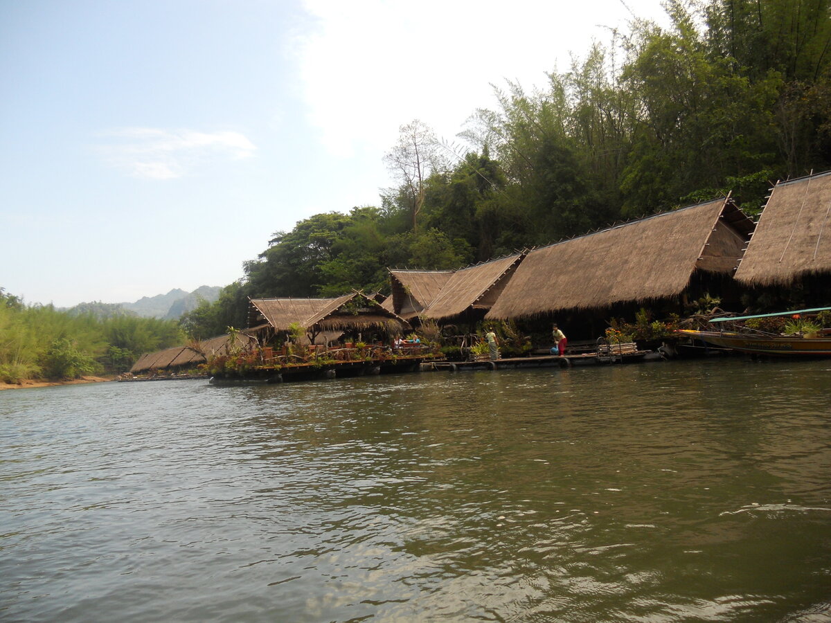 Сегодня продолжаю рассказ о  нашем пребывании на отдыхе в королевстве Тайланд. Первая экскурсия, которая длилась 2 дня, была в самое сердце джунглей, на реку Квай.  Уникальность этой экскурсии состояла в том, что нас разместили в необычном отеле. Это плавучий отель на реке Квай. Деревянные бунгало на два номера закреплены на понтонах, и соединены между собой паровозиком. Ощущение умиротворённости, душевного спокойствия и релакса – это те чувства, которые испытываешь здесь. Здесь нет электричества (его заменяют керосиновые лампы), нет интернета, мобильной связи и горячей воды. Да это и не нужно. Бунгало сделаны в стиле кантри: соломенные крыши, всё в экзотических цветах, огромный деревянный стол с лавкой на веранде, гамак, в комнате большая кровать с москитной сеткой, небольшой пирс с шезлонгами.