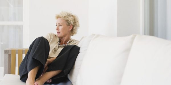 Mature woman sitting on sofa, looking away in thought