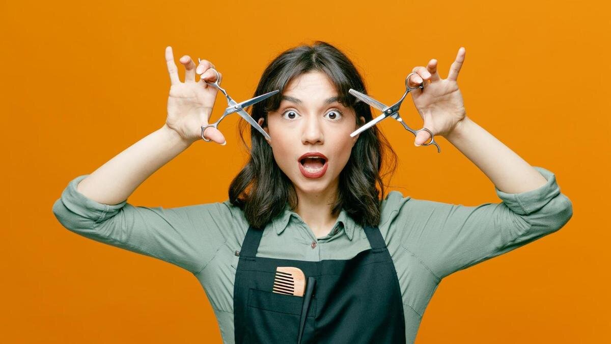    Девушка с широко открытыми глазами держит ножницы возле лица:Freepik/stockking