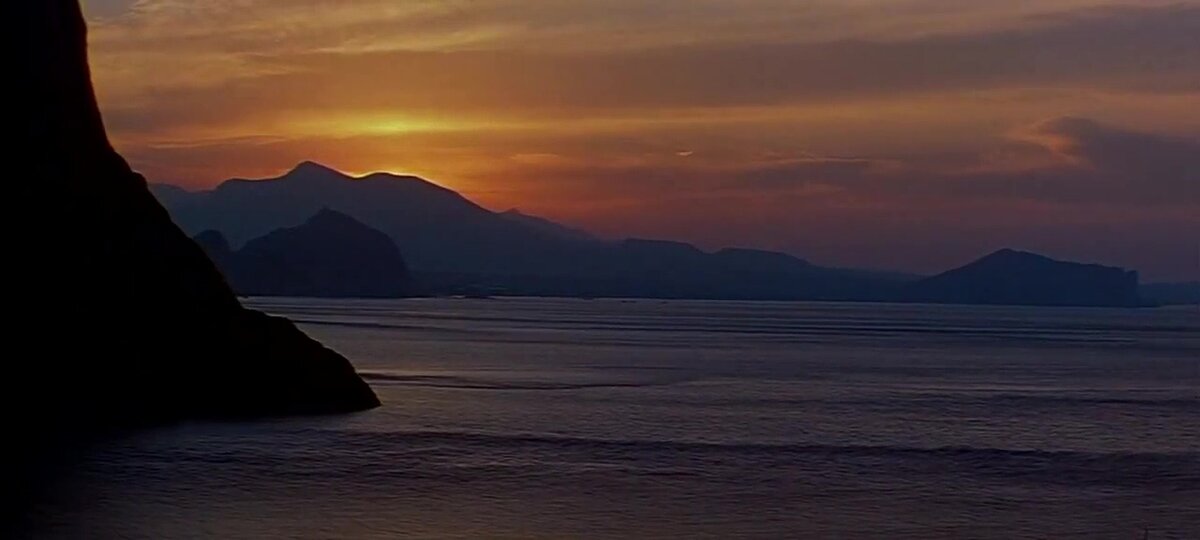 Кадр из фильма «Пираты XX века». Вид с мыса Капчик в сторону города Судак. Видны Крепостная гора (где находится Генузская крепость) и мыс Алчак (крайний справа). Между ними расположены судакские пляжи.