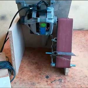  
Если Вам нужен ленточный шлифовальный станок, то его можно сделать своими руками, как вариант можно использовать вот такую простую конструкцию, которая сделана из двигателя от стиральной машины, а в качестве натяжителя ленты использован дверной доводчик. 
Материалы для изготовления самоделки: