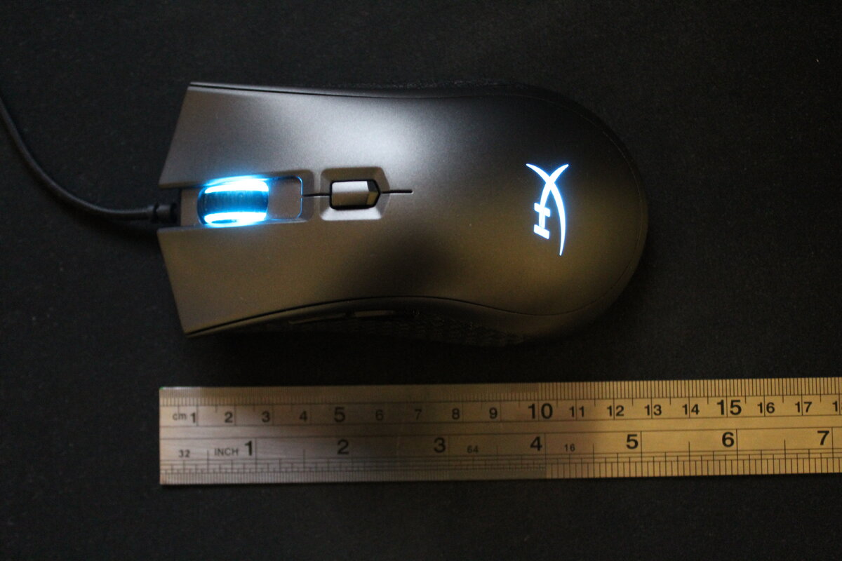 Верхняя шкала линейки — сантиметры, нижняя — дюймы. В ширину мышь примерно 6,5 см в середине, чуть расширяется к началу и концу примерно до 7 см.