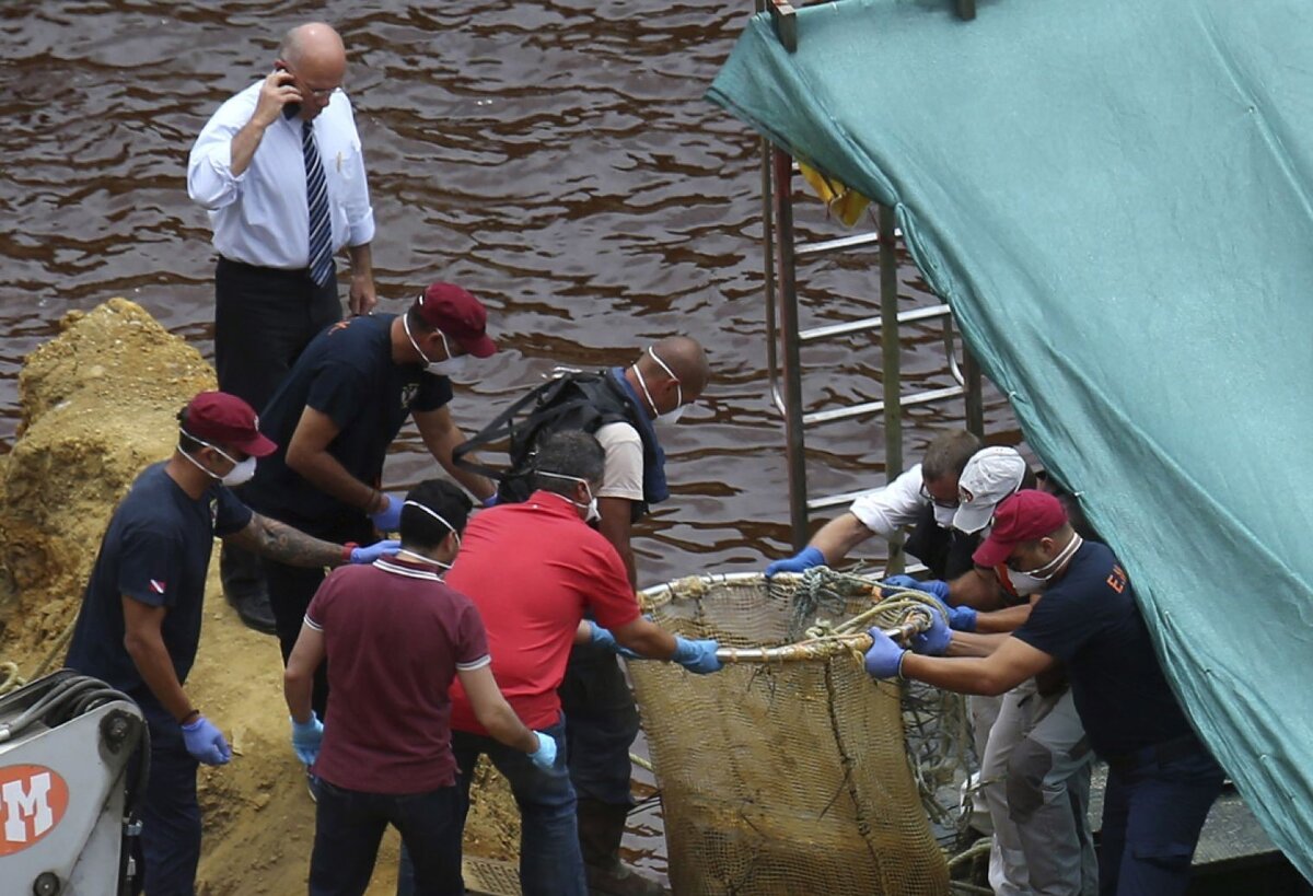 Кипрское подразделение специального реагирования на стихийные бедствия и следователи перевозят чемодан с лодки после того, как он был извлечен из искусственного озера недалеко от деревни Мицеро, недалеко от столицы Никосии, Кипр, во вторник, 4 июня 2019 года. (AP Photo / Petros Karadjias )
