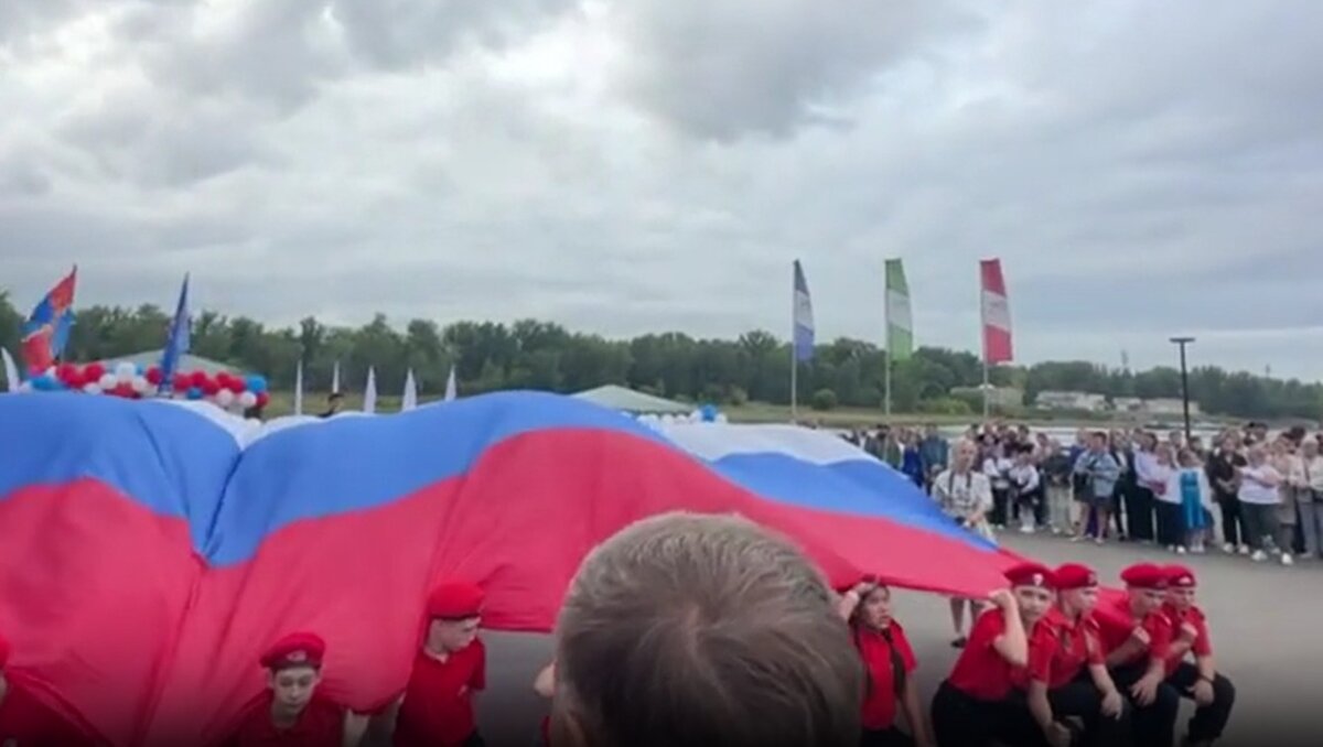 В Красноярске школьники слушали гимн на коленях с огромным флагом РФ на руках