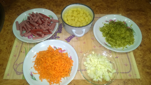  Пока мясо варится, можно нарезать все оставшиеся продукты: колбаски, картофель, лук. Морковь и огурец следует натереть на крупной терке.
