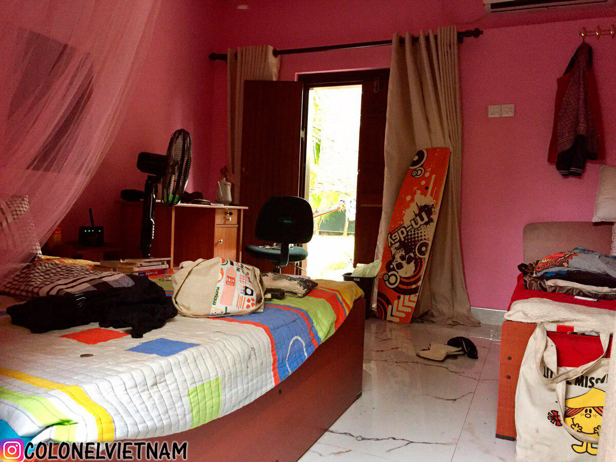 Небольшая спальня с кондиционером, окном и компьютерным столом.