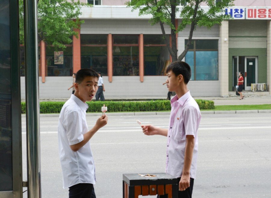 Парни на автобусной остановке ждут транспорт. 