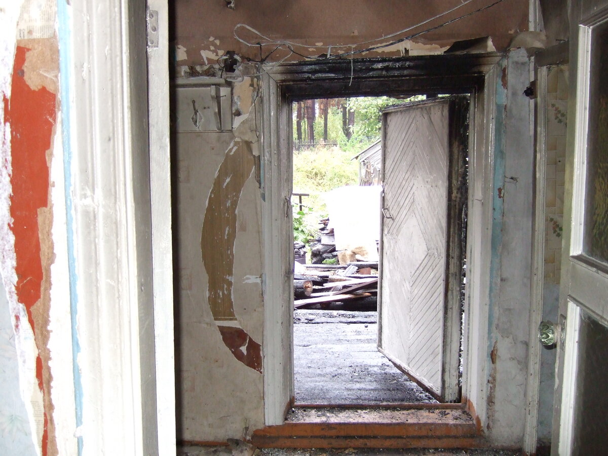 Выход из дома на улицу. Веранды пока нет. Зимой наметало сугробы прямо до дверей. Видно как огонь пытался прорваться в дом, но дверь остановила огонь.