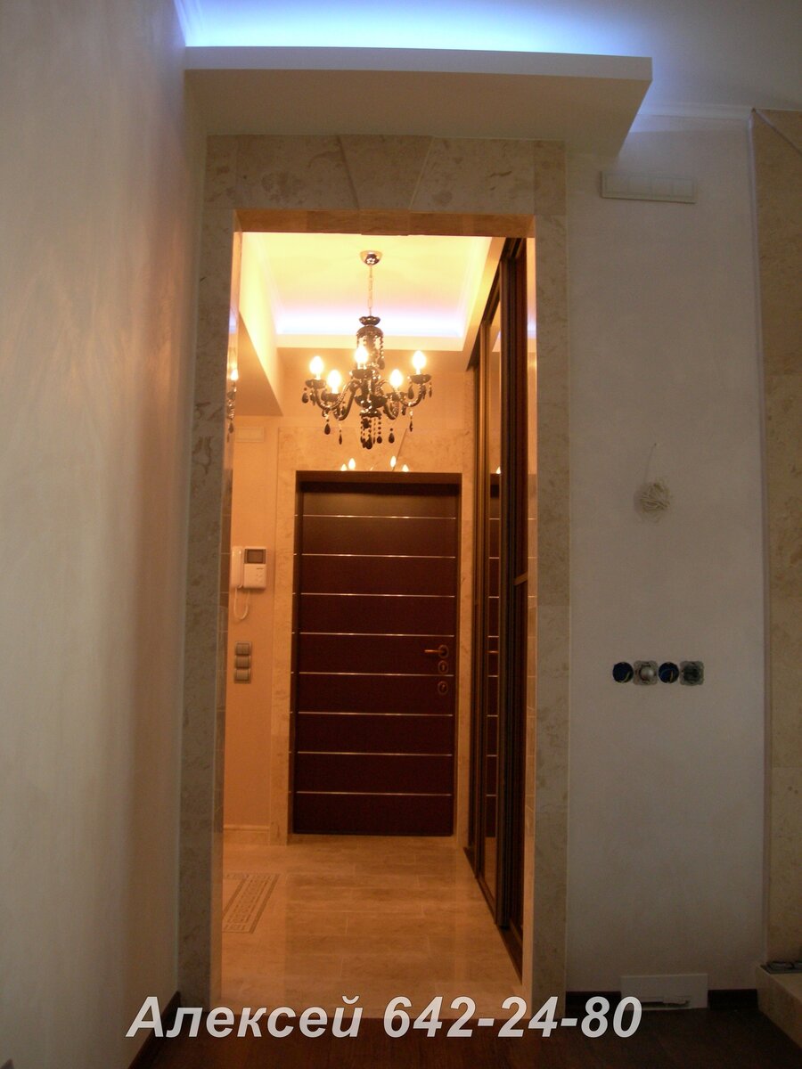 На фото портал и пот из мрамора. Облицовка портала входной зоны и проход в гостинную выполнена в одном стиле.