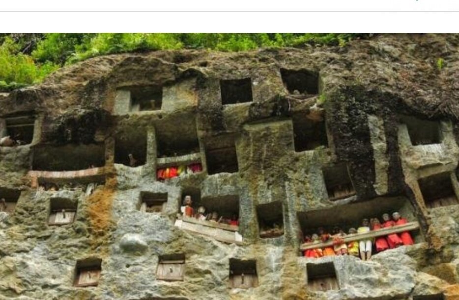 Могилы выкопаны на скалистой горе и украшены деревянными чучелами умерших.