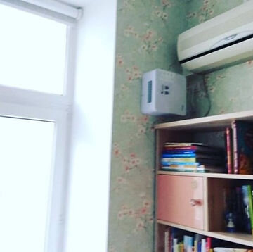Бризер Тион Лайт между книжными полками и кондиционером