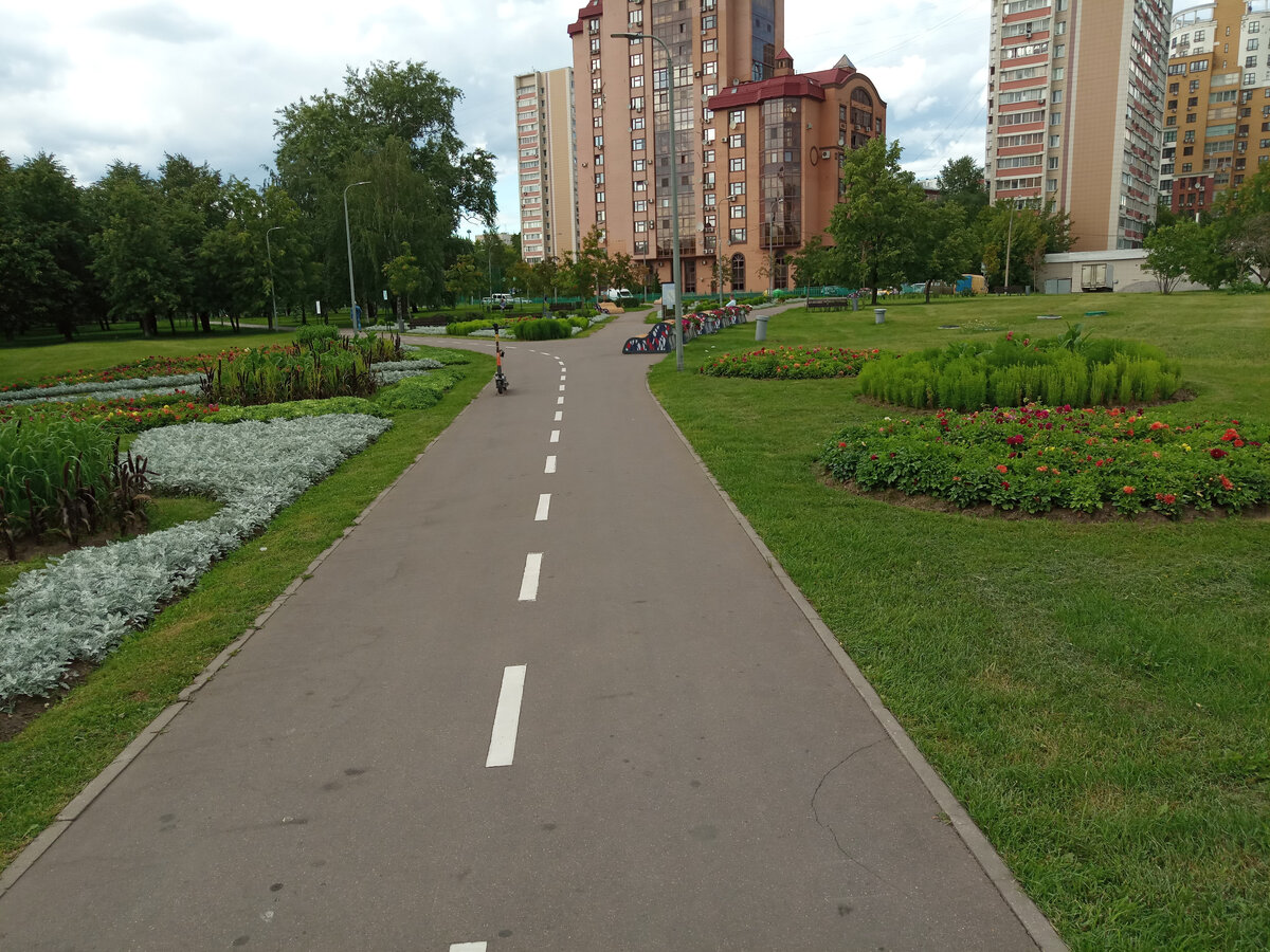 Уютный кусочек парка. Вдалеке можно заметить людей на скамейках.