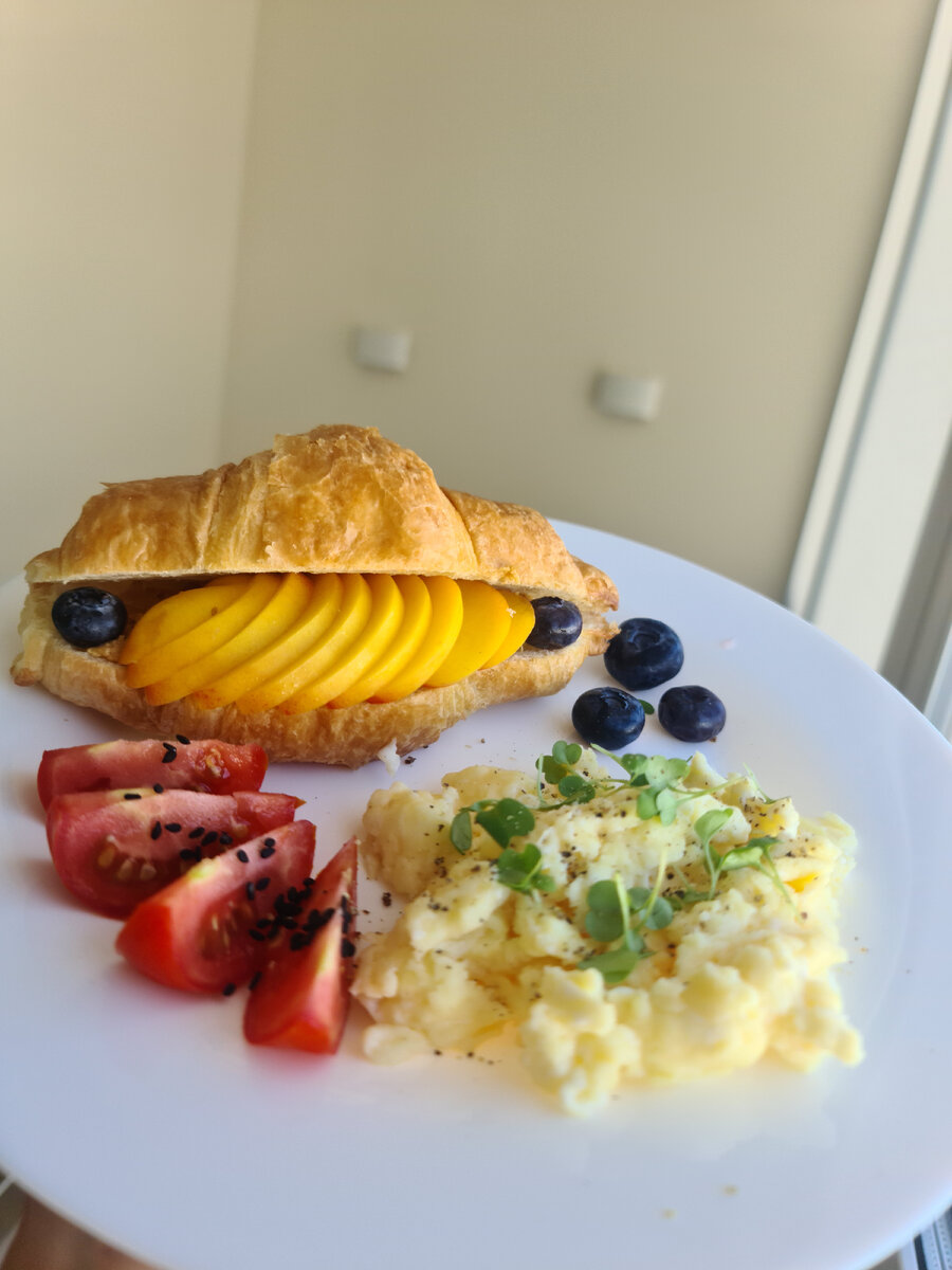 Омлет, круассан, овощи и ягоды.