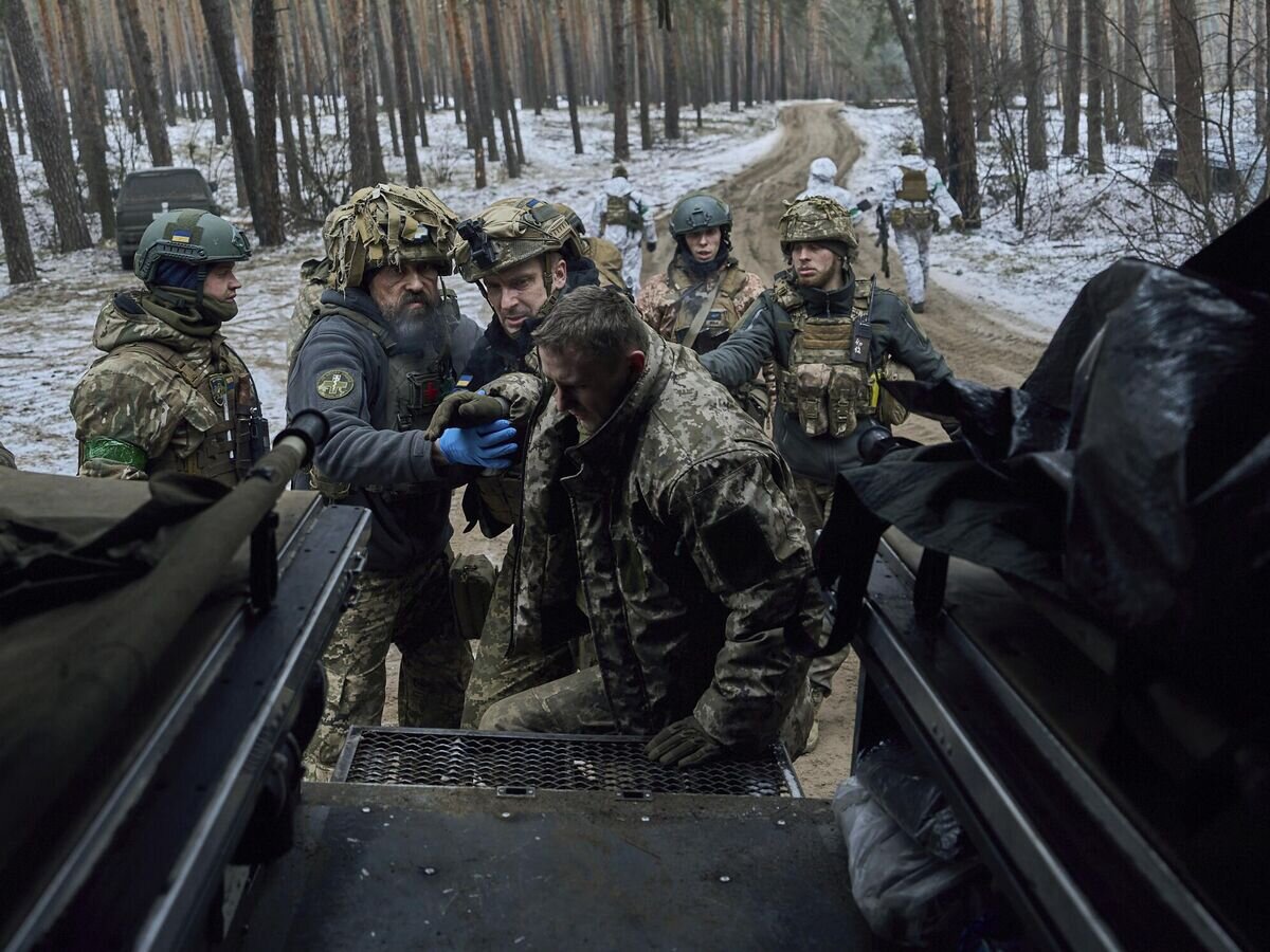    Медики помогают раненому украинскому солдату© AP Photo / LIBKOS