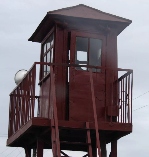 Вышка очень похожая на нашу. Площадка была вровень забором, а по верху забора - колючая проволока. У нашей площадка была пошире и солдат с ружьём мог свободно развернуться.