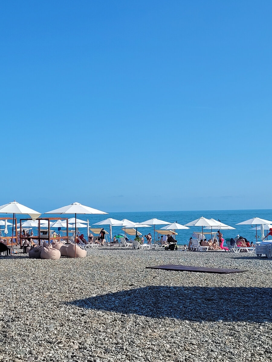 Широкая пляжная полоса с жезлонгами, зонтиками, качелями и шатрами. Фото автора