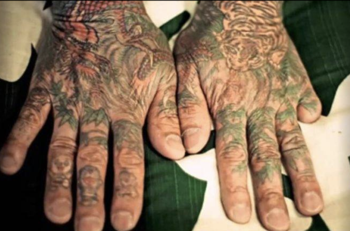 Якудза, его руки покрыты татуировками, отсутствующий мизинец, показывает что он гангстер .