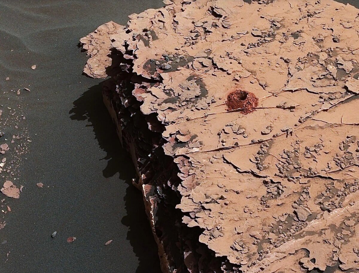 Марсоход НАСА "Curiosity" пробурил это отверстие глубиной в два дюйма в марсианской скале в рамках своих исследований состава почвы на красной планете.