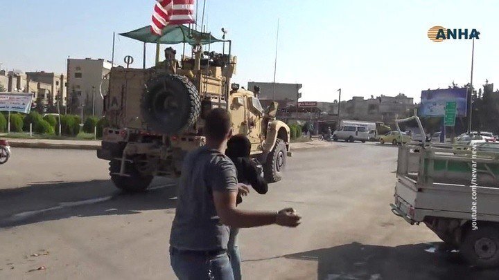 Курды бросают камни у военную колонну США, которые покидают базу и оставляют курдов без поддержки.