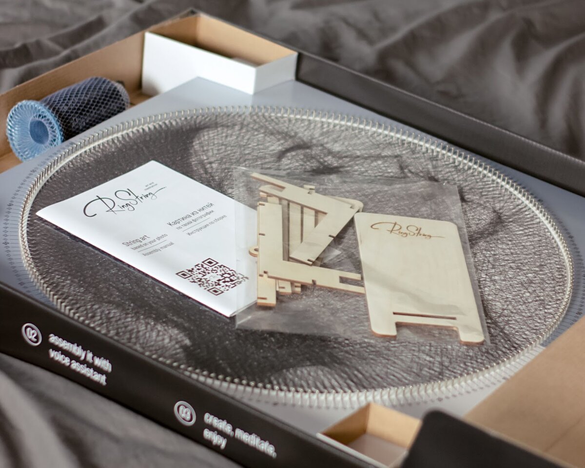 В комплект входит основа с 240 гвоздями, нить длиной 5 км, коробка-мольберт (на ней удобно собирать картину), крепление для нити, подставка для телефона, подробная инструкция с QR-кодом и восьмизначным кодом для доступа к генератору, а также крепление на стену 