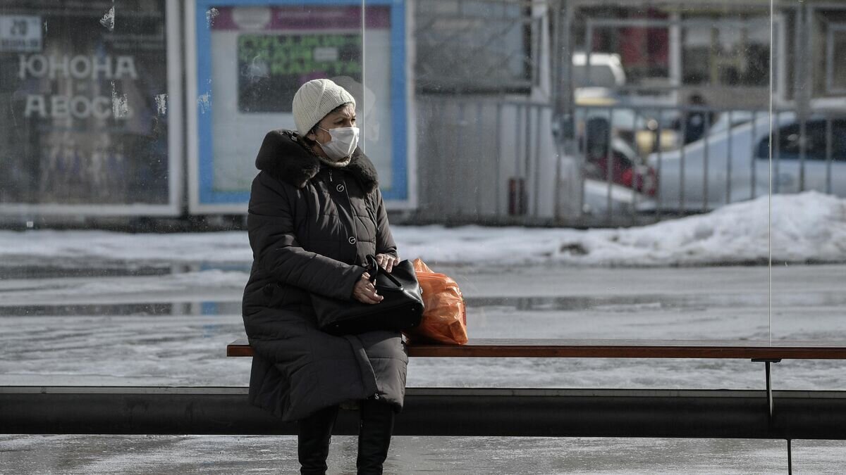    Пожилая женщина в защитной маске на остановке общественного транспорта в Симферополе© РИА Новости / Константин Михальчевский