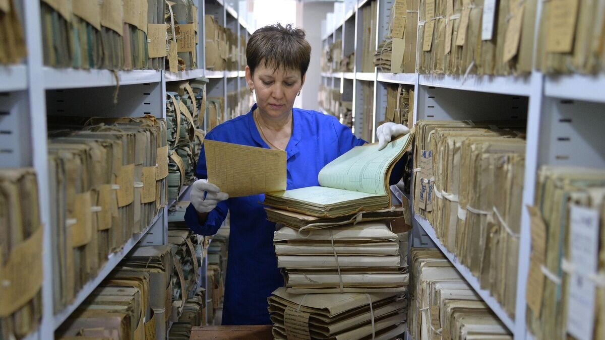    Сотрудница разбирает папки с документами в Государственном архиве Челябинской области© РИА Новости / Александр Кондратюк